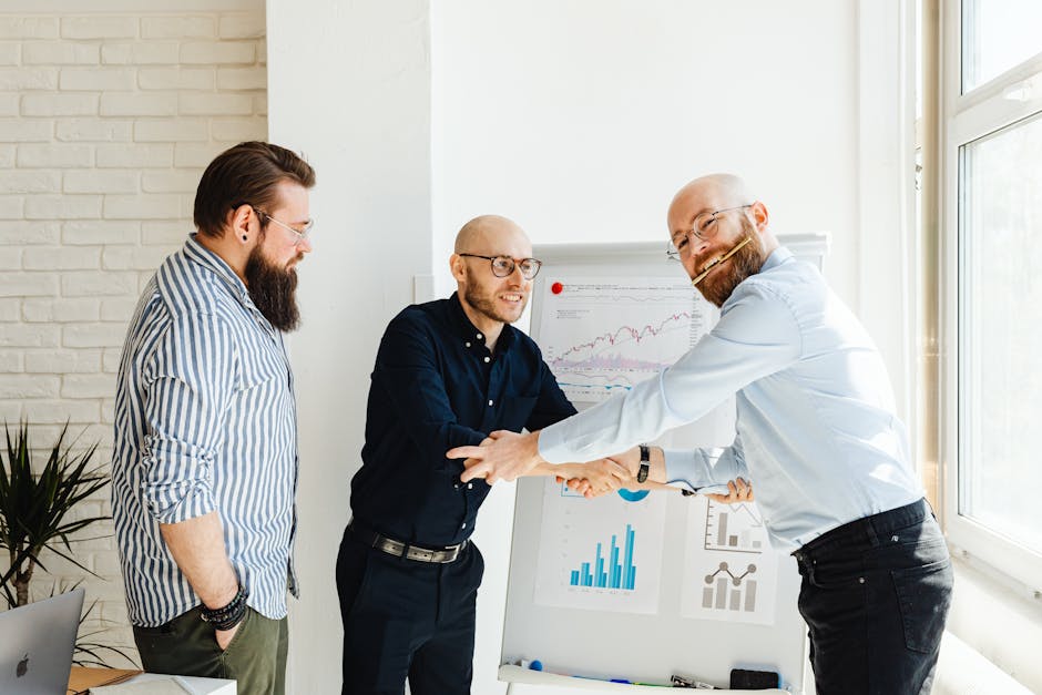 Three businessmen engage in a lively discussion around a whiteboard with charts in a sunlit office.